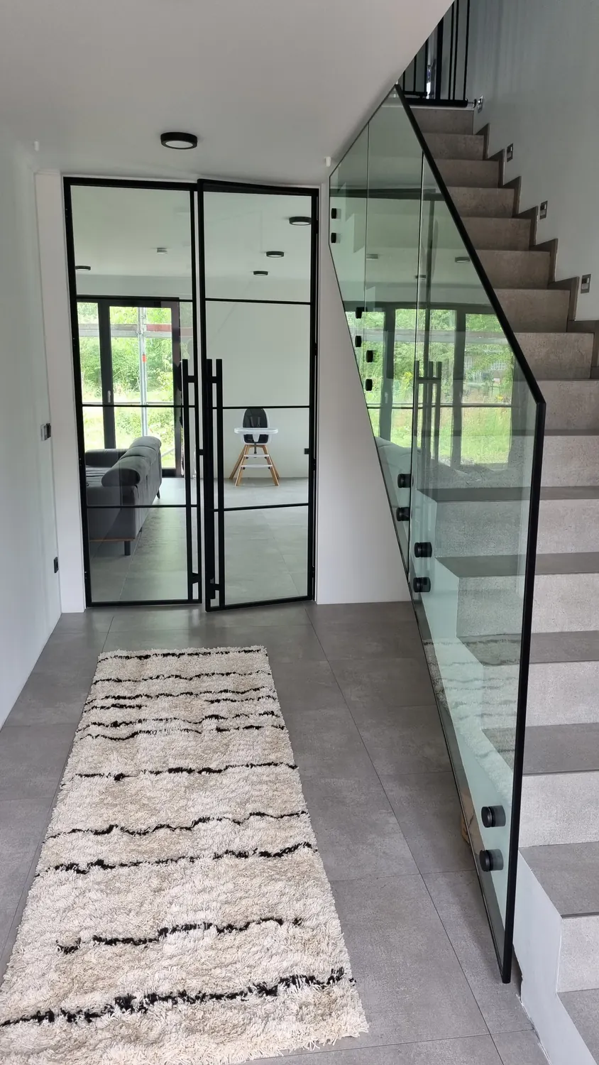 Lofttür und Glaswand neben einer Treppe mit Ganzglas-Geländer